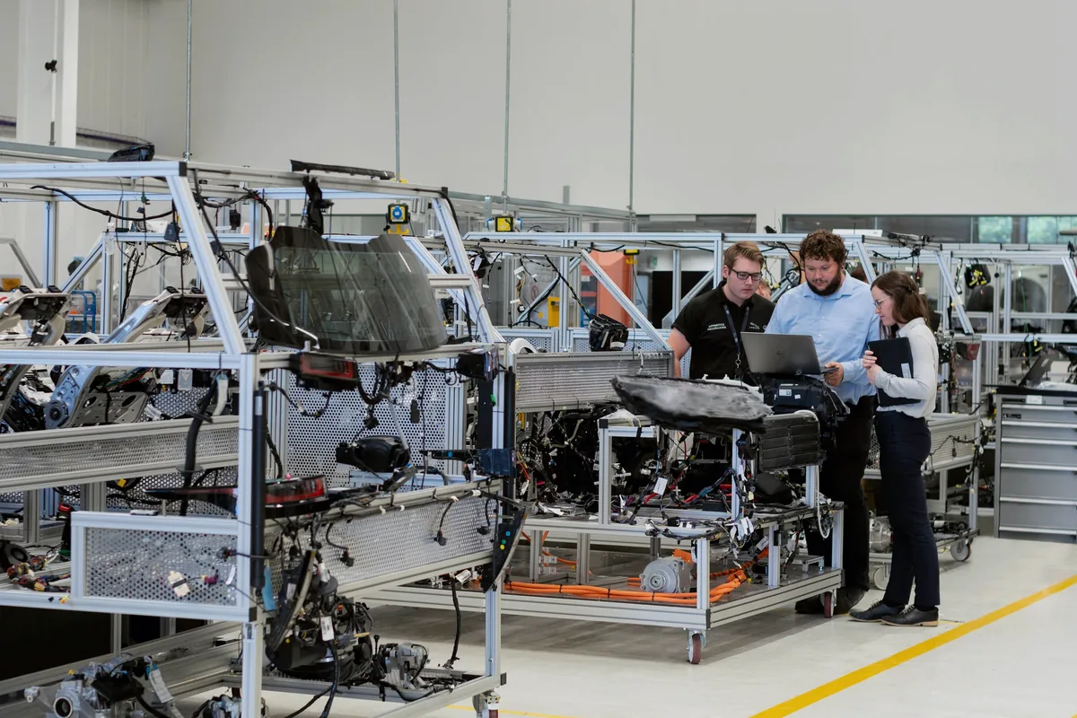 Cross-functional engineering team collaborating with digital tools in a manufacturing facility