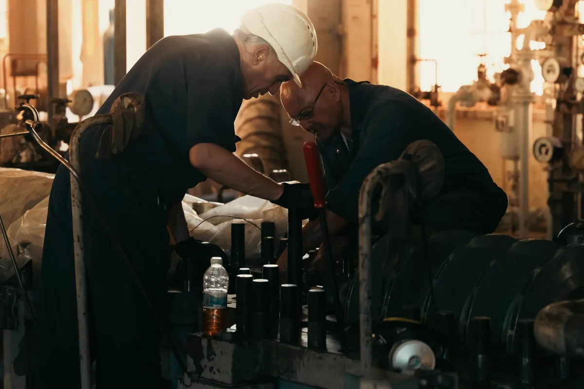 Two engineers collaborating while inspecting industrial machinery