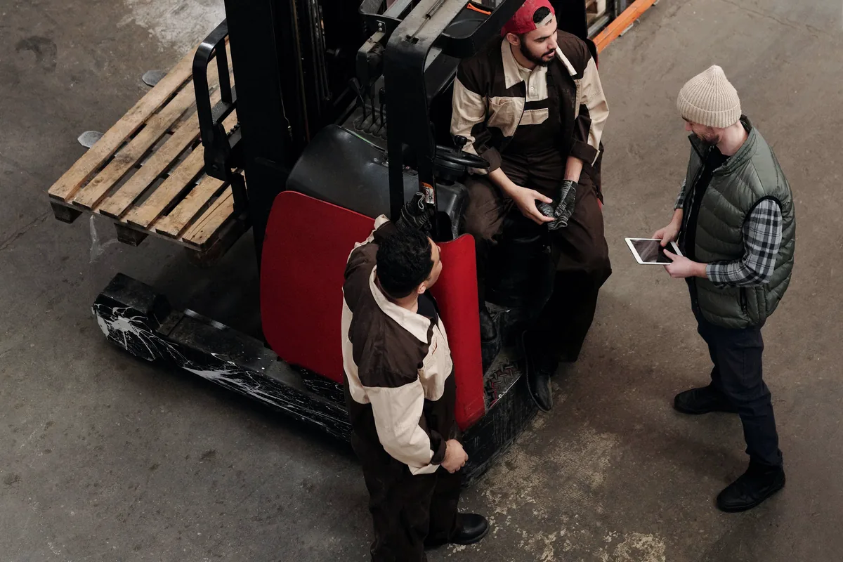 Warehouse manager and operators discussing market and operational questions around a tablet